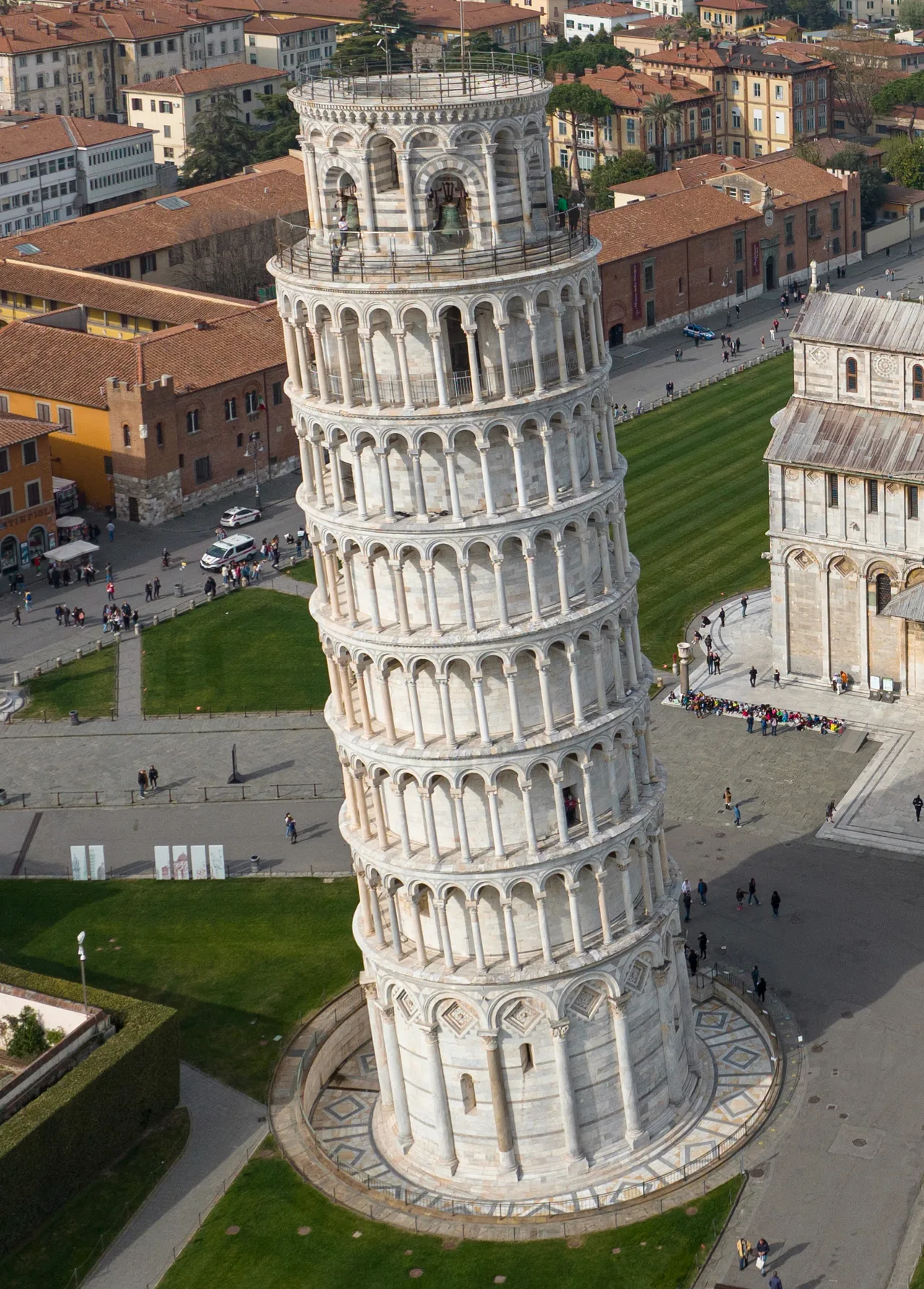 The leaning bell tower of Pisa; a cylindrical marble body of stacked blind-arcade galleries on slender columns