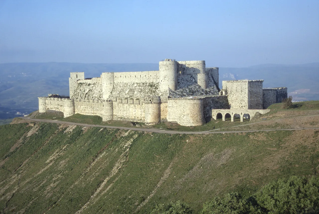 The two nested rings of walls of Krak des Chevaliers and the thick sloped stone skirt (glacis) wrapping the inner castle