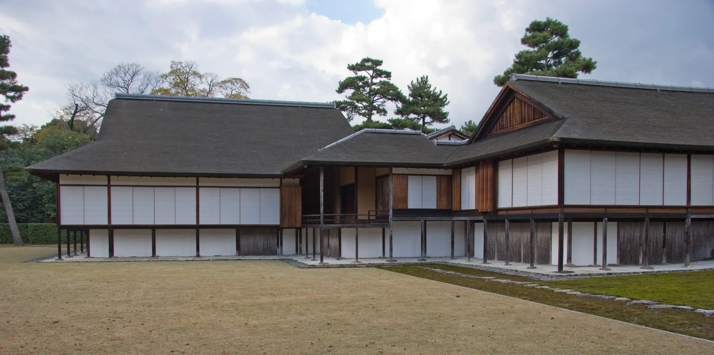 The timber structure of Katsura Villa opening to the garden; sliding screens, the engawa under the eaves, and the pond edge