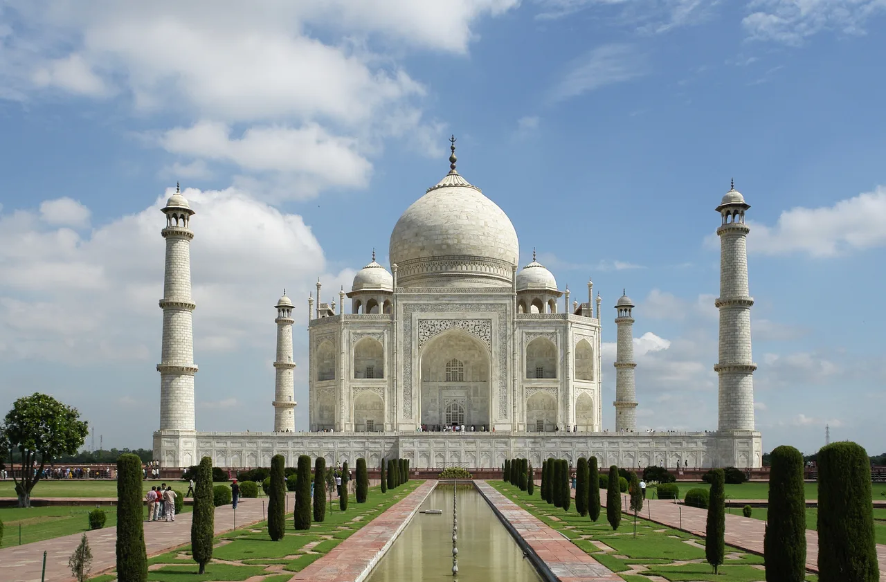 The white marble tomb of the Taj Mahal with its onion dome, four minarets, and the reflecting pool before it