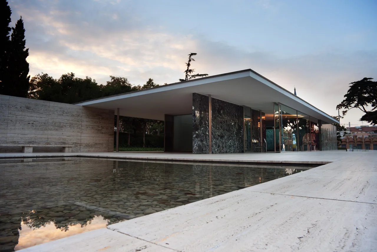 The free marble wall planes, slender steel columns, reflecting pool, and flat roof slab of the Barcelona Pavilion