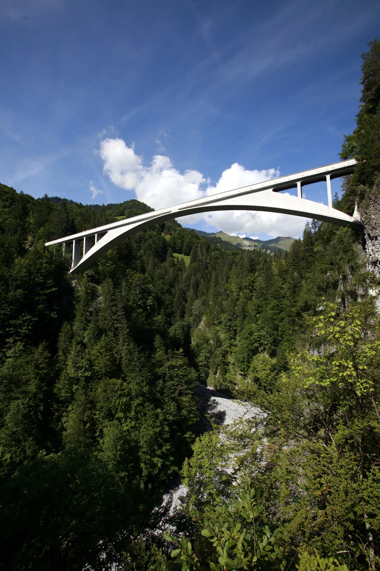 The reinforced-concrete arch of Salginatobel Bridge crossing a deep Alpine valley, slender at the centre and widening at the supports