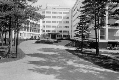 The long patient wing of the Paimio Sanatorium: strip windows and balconies along a white façade, surrounded by pine forest