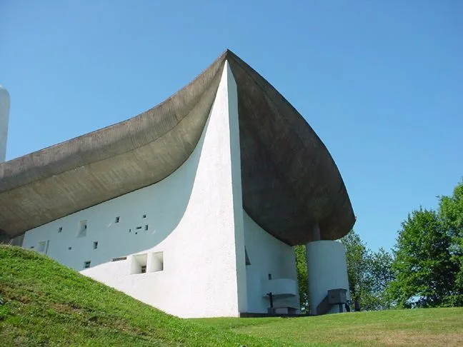 The curving white walls of the Ronchamp Chapel and its dark, sculptural reinforced-concrete roof sagging downward