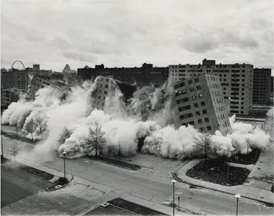 One of the Pruitt-Igoe blocks collapsing under demolition charges, tipping sideways in a cloud of dust