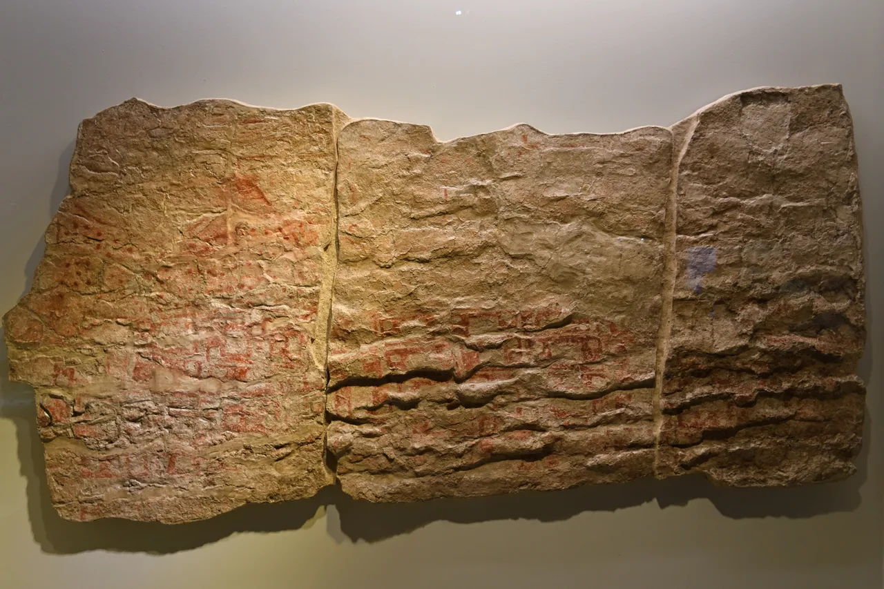 Çatalhöyük duvar resmi: alt sırada dörtgen birimler, üstte iki tepeli, püskürür gibi görünen bir desen