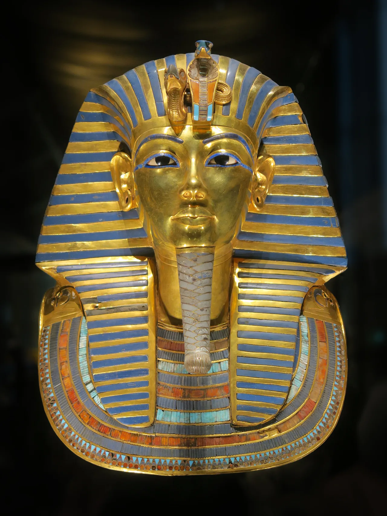 Front view of Tutankhamun's golden funerary mask: striped nemes headdress, blue eyes, idealised face