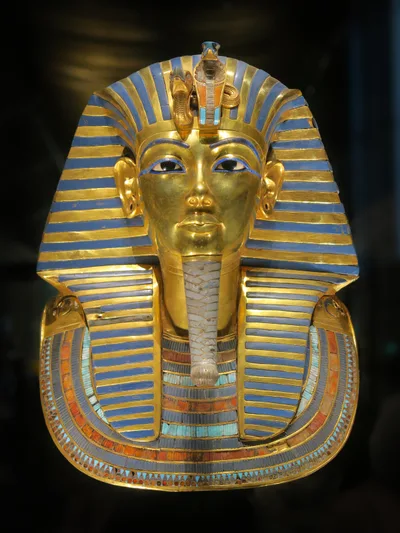 Front view of Tutankhamun's golden funerary mask: striped nemes headdress, blue eyes, idealised face