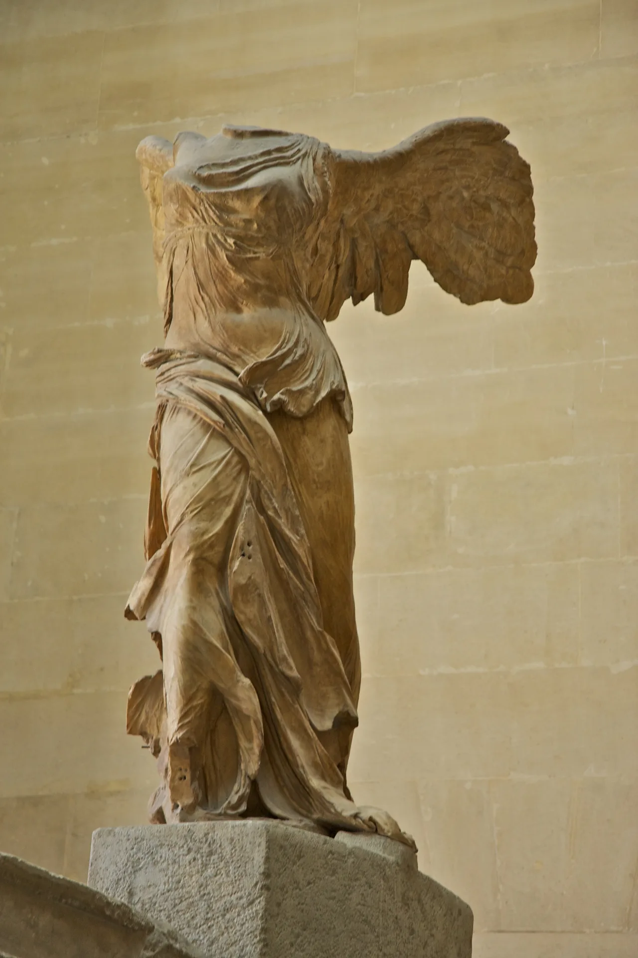 The headless and winged marble statue of Nike with wind-swept drapery exhibited at the top of the Daru staircase in the Louvre Museum
