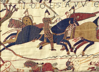 A scene from the Bayeux Tapestry: Norman warriors advancing on horseback with clubs, with a Latin inscription above
