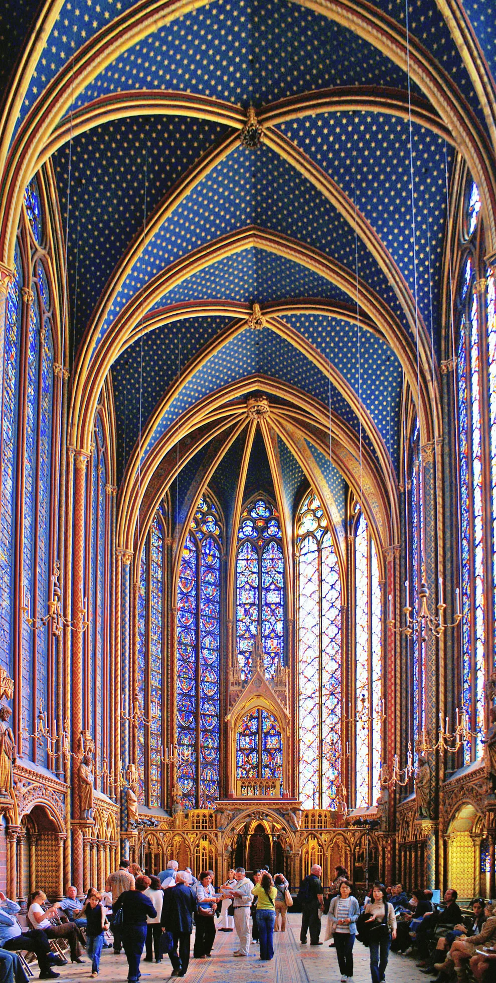 Interior view of the upper chapel of Sainte-Chapelle: between slender stone columns, vast 15-metre stained-glass windows in cobalt blue, red and gold