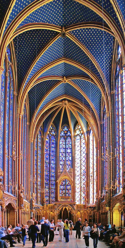 Interior view of the upper chapel of Sainte-Chapelle: between slender stone columns, vast 15-metre stained-glass windows in cobalt blue, red and gold