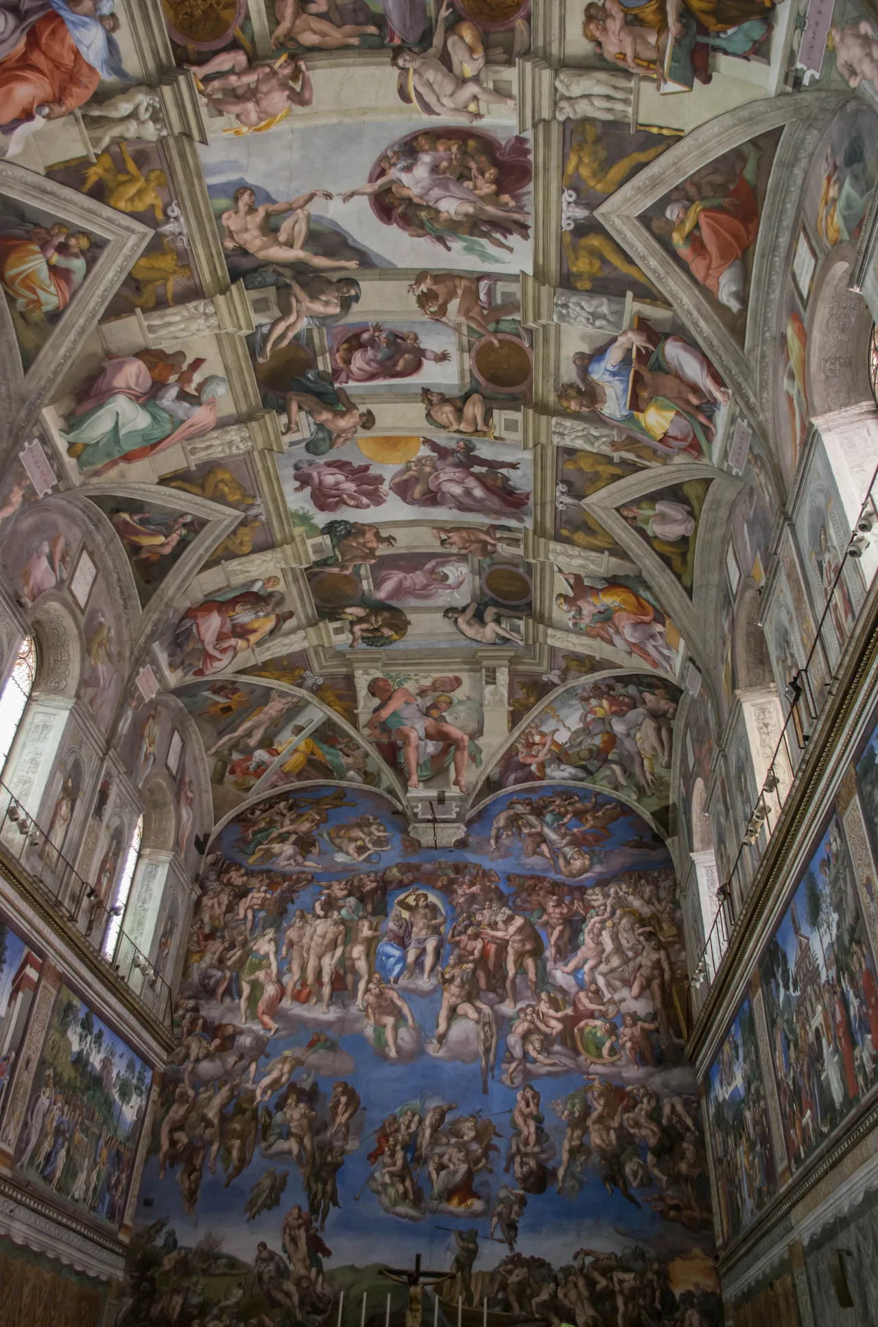 The frescoed Sistine Chapel ceiling: nine rectangular panels of Creation scenes set inside a painted architectural framework, surrounded by prophets and sibyls