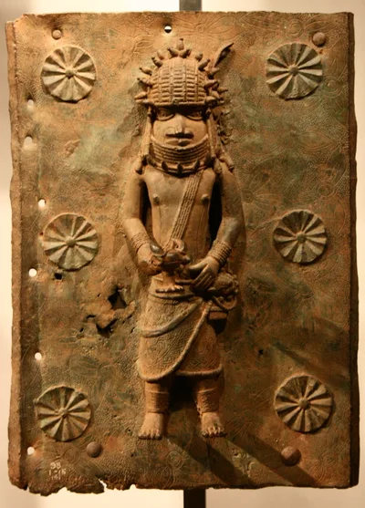 A Benin brass plaque: court figures in relief wearing coral-bead collars and headdresses