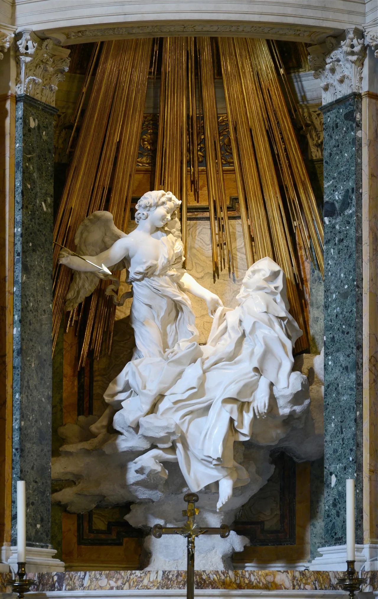 Bernini's marble group: Teresa half-reclining on clouds with an angel holding a golden arrow above her, gilded rays of light behind them
