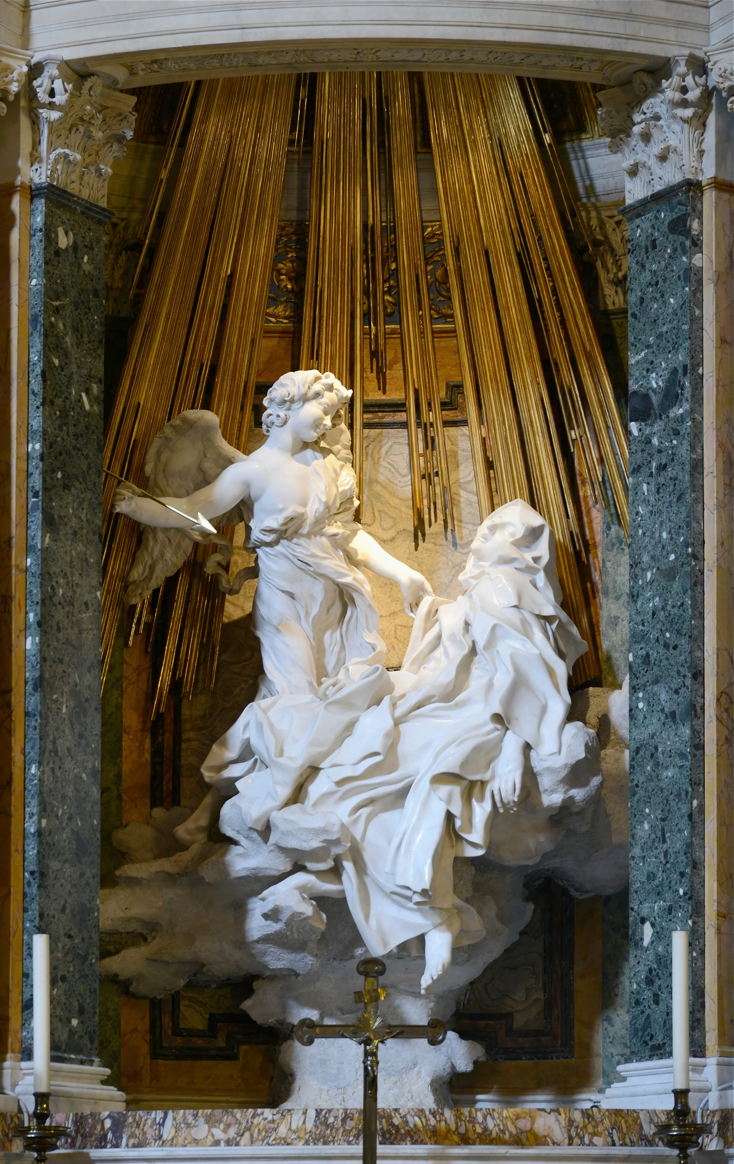 Bernini's marble group: Teresa half-reclining on clouds with an angel holding a golden arrow above her, gilded rays of light behind them