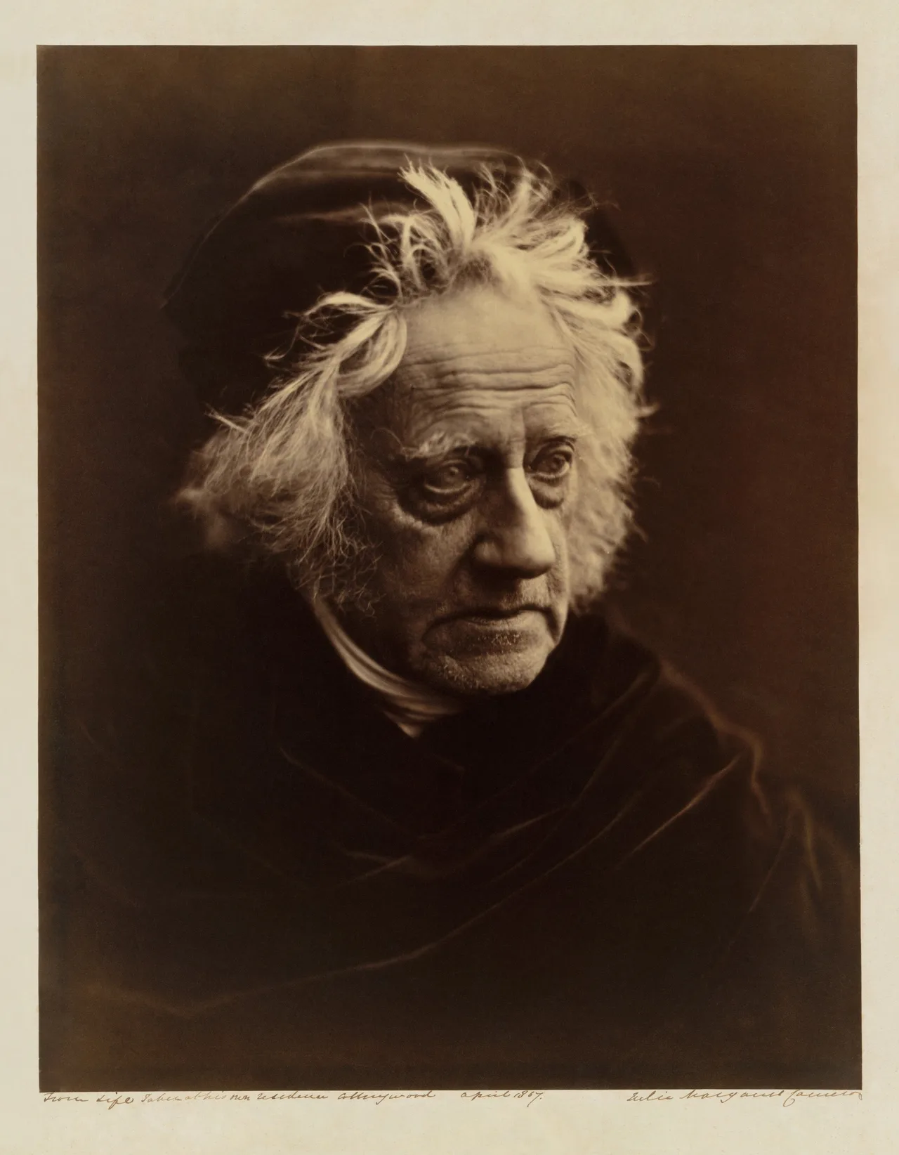 Julia Margaret Cameron's portrait of John Herschel: a close view of an elderly man with dishevelled white hair against a dark ground