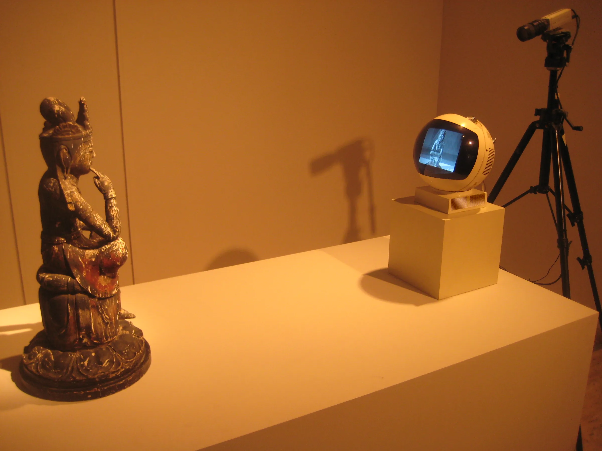 TV Buddha: a Buddha statue seated before a television screen showing its own image
