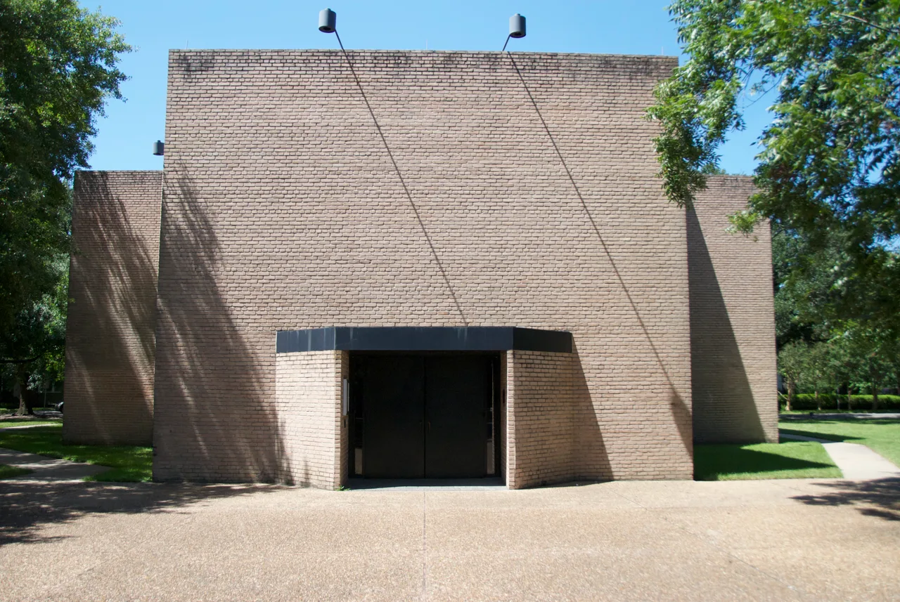 Exterior of the Rothko Chapel: a soft-roofed bare brick facade and Barnett Newman's Broken Obelisk in the reflecting pool in front