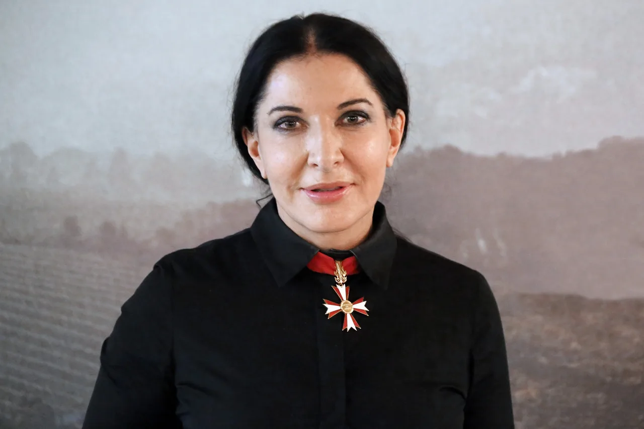 In MoMA's atrium, Marina Abramović sits in a red robe and looks directly at the stranger sitting opposite her