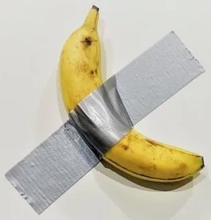 A ripe yellow banana duct-taped to a grey gallery wall with a strip of silver tape