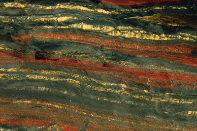 Polished cross-section of an iron-rich rock showing alternating thin bands of dark red and black