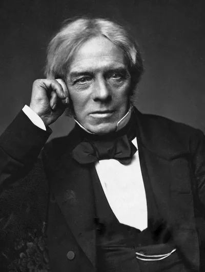 A seated photograph of Michael Faraday: a middle-aged man in a dark suit with a calm gaze