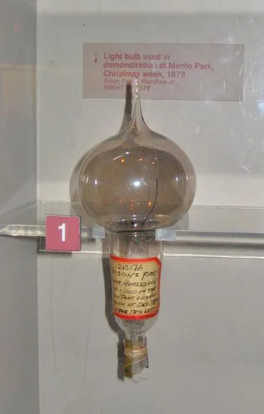 Photograph of an early Edison incandescent lamp: pear-shaped glass bulb with a horseshoe-shaped carbonised filament and a screw base