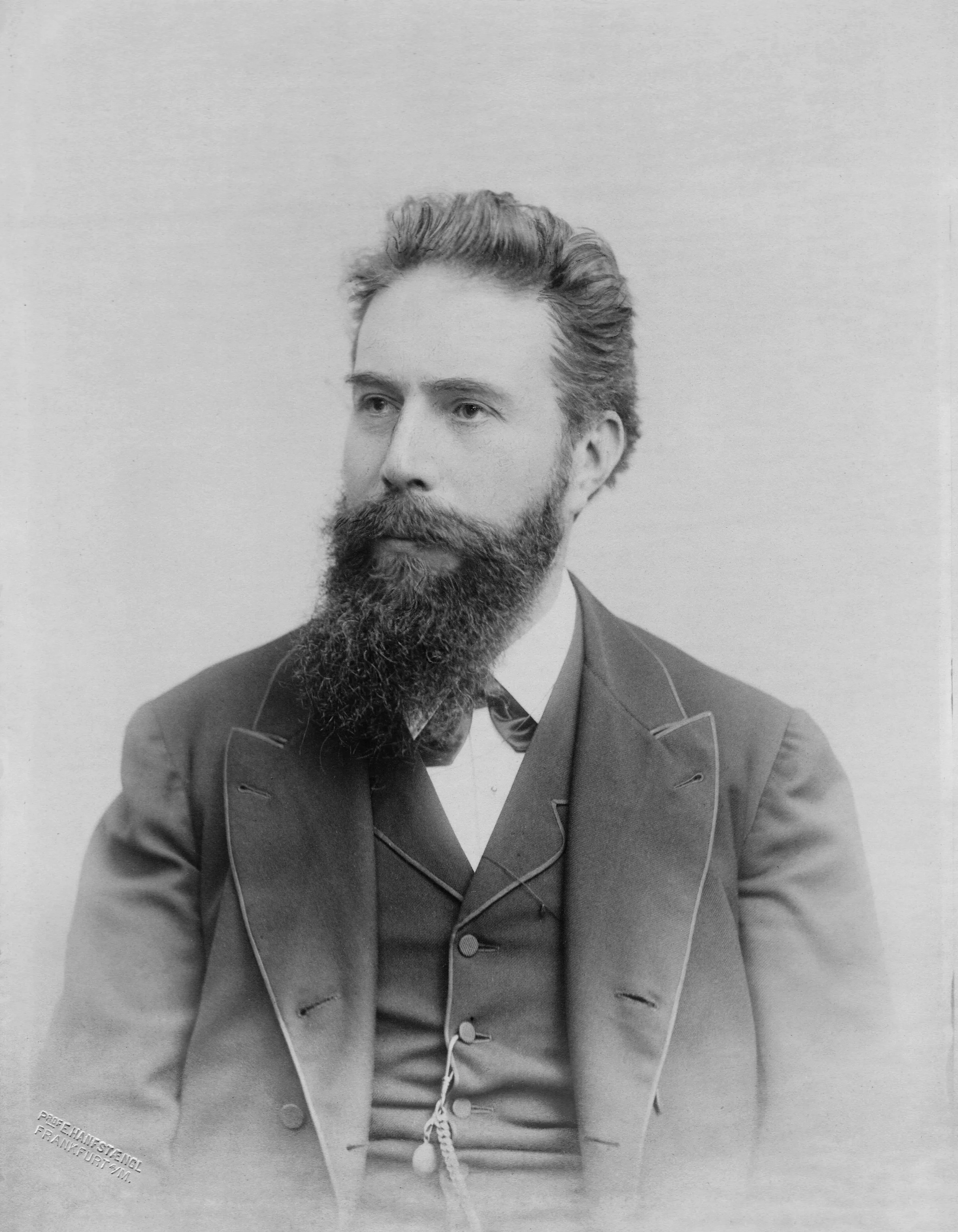 A portrait photograph of Wilhelm Röntgen: a bearded man in a dark suit with a serious gaze