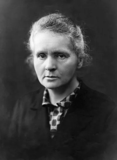 A portrait of Marie Curie from around the 1920s: a middle-aged woman in dark clothing with a serious expression