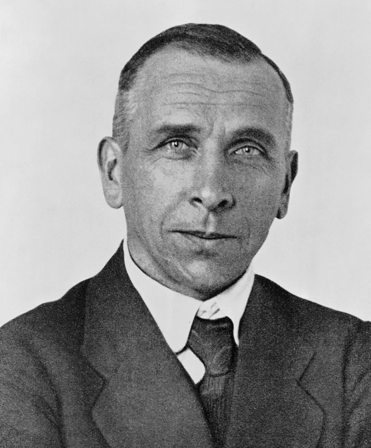 Black-and-white portrait of Alfred Wegener taken between 1924-1930: a middle-aged man in a thick coat, with a moustache, smoking a pipe