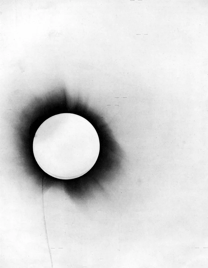 Negative of the 1919 eclipse photographic plate: the corona around a dark disc with marked stars