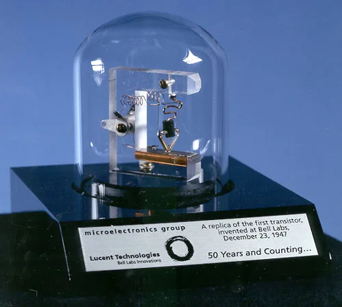 Replica of the first point-contact transistor: two thin rods with fine metal wires at their tips touch a small piece of germanium atop a triangular plastic block