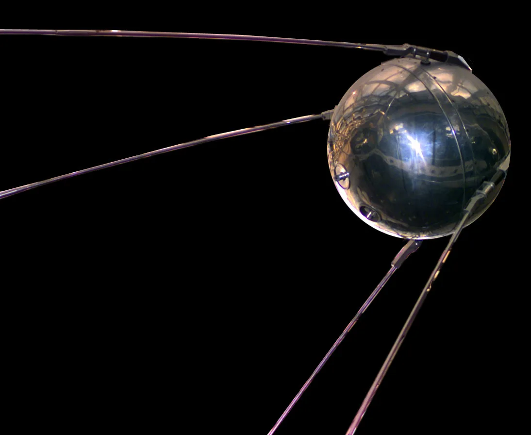 A full-scale replica of Sputnik 1: a polished silver sphere with four long thin antennae trailing backward from its sides