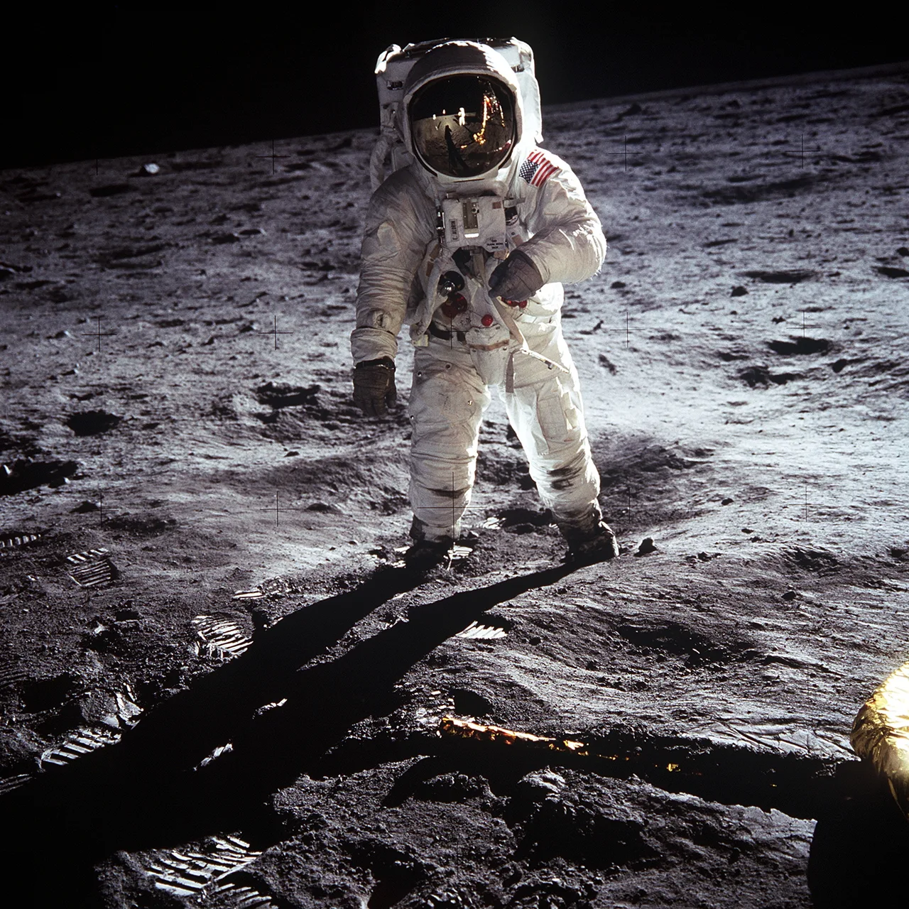 Apollo 11'in beyaz astronot kıyafetli Buzz Aldrin'i, Ay'ın gri kül yüzeyinde tek başına dururken; kaskındaki visörde ay modülü ve fotoğrafı çeken Armstrong yansıyor