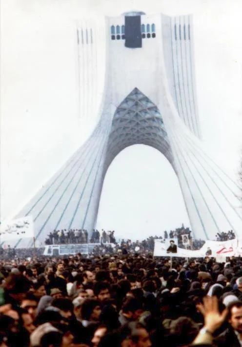 February 1979 photograph: tens of thousands of demonstrators completely filling the wide square in front of the Shahyad (later Azadi/Freedom) Tower in Tehran, with the arched white monument rising in the background