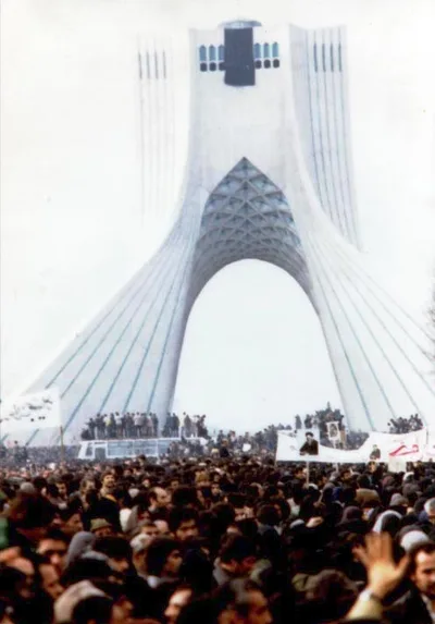 February 1979 photograph: tens of thousands of demonstrators completely filling the wide square in front of the Shahyad (later Azadi/Freedom) Tower in Tehran, with the arched white monument rising in the background