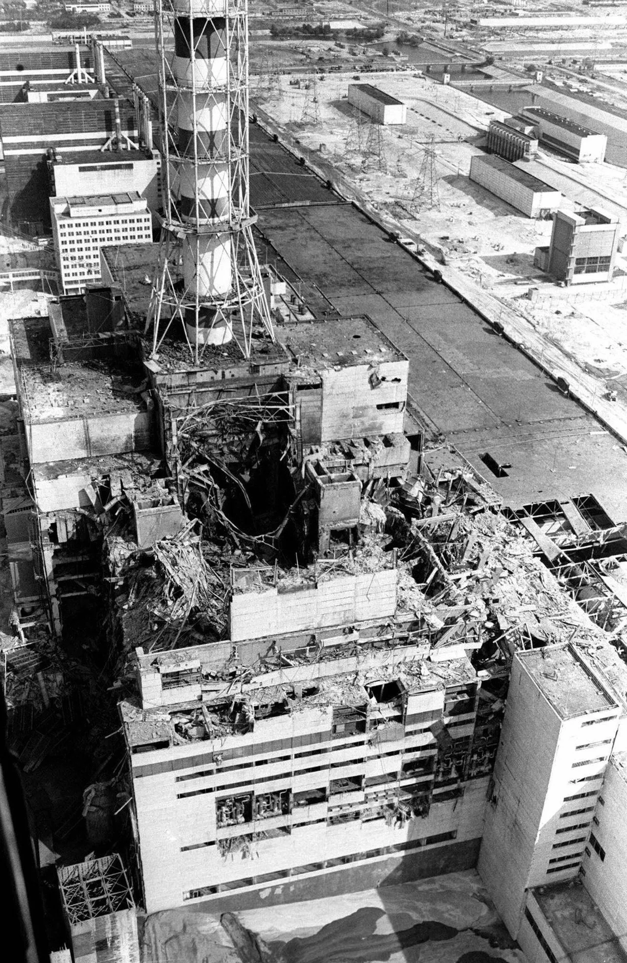 Black-and-white 1986 aerial photograph from a helicopter: the destroyed Reactor No. 4 building seen from above, its roof collapsed, with construction equipment and debris around it