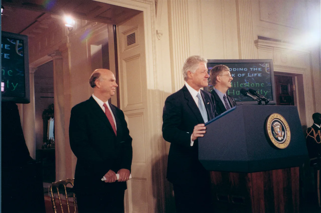 A White House press conference with three men side by side — Craig Venter of Celera on the left, President Bill Clinton at the podium in the centre, and Francis Collins of NIH on the right; U.S. and NIH flags behind them
