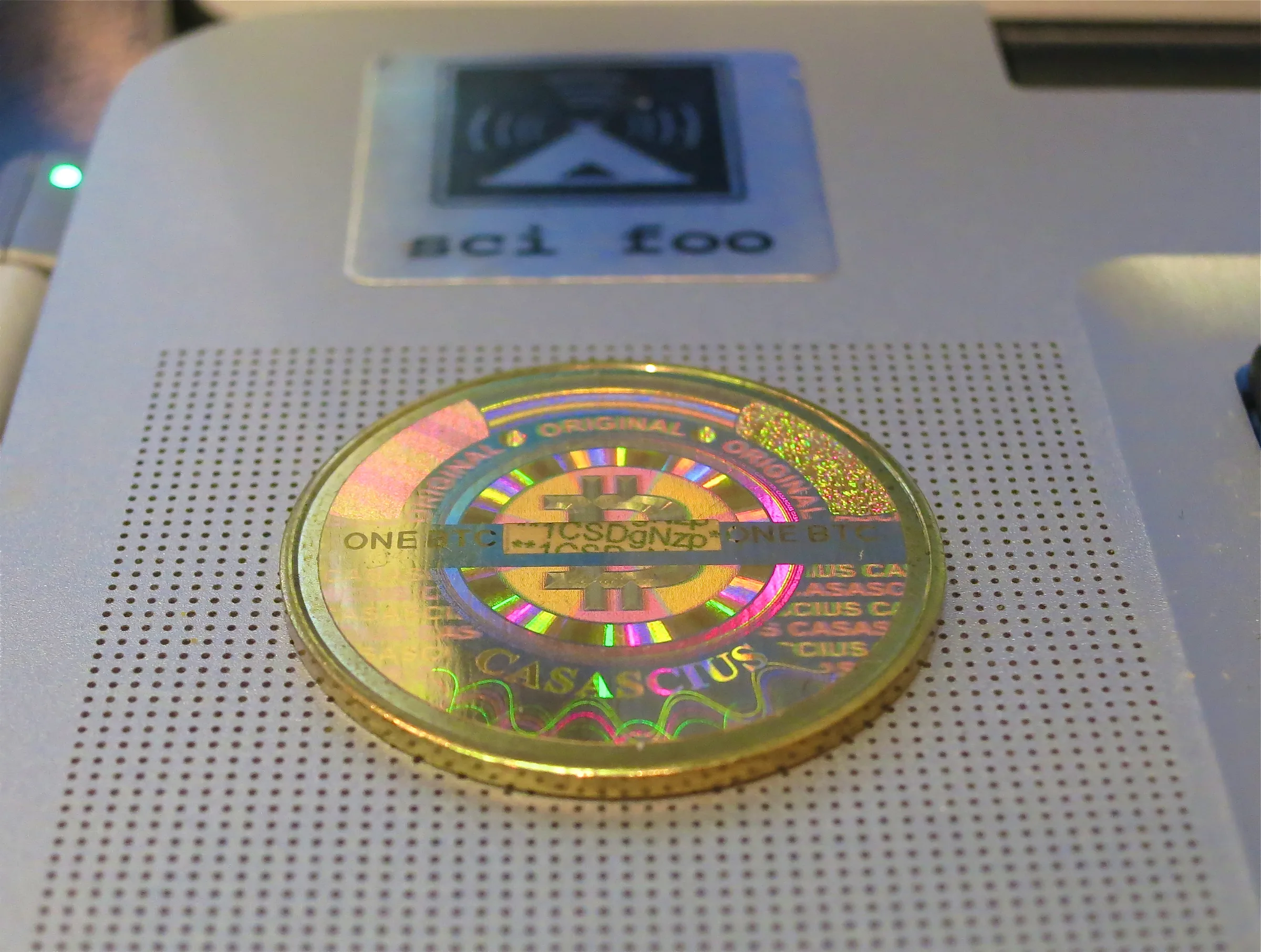 Pirinçten yapılmış fiziksel Casascius madeni parası, üzerinde Bitcoin amblemi (B harfi) ve bir hologramla mühürlenmiş özel anahtar — koyu zeminde tek bir madeni para
