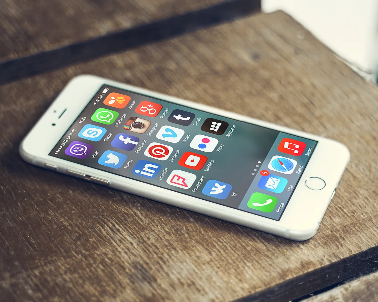 A close-up of a smartphone screen: a grid of colourful icons for social media apps including Facebook, Instagram, WhatsApp, Twitter, YouTube, and Snapchat