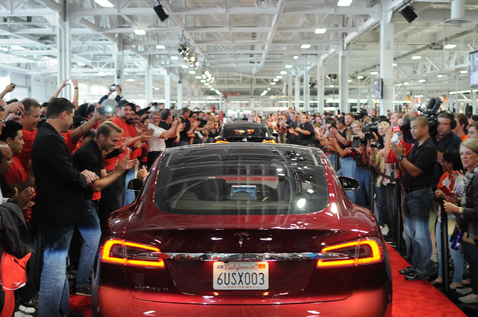 22 Haziran 2012, Fremont Tesla fabrikasında ilk müşteri teslimatları için art arda dizilmiş kırmızı Tesla Model S sedanları geçit töreni