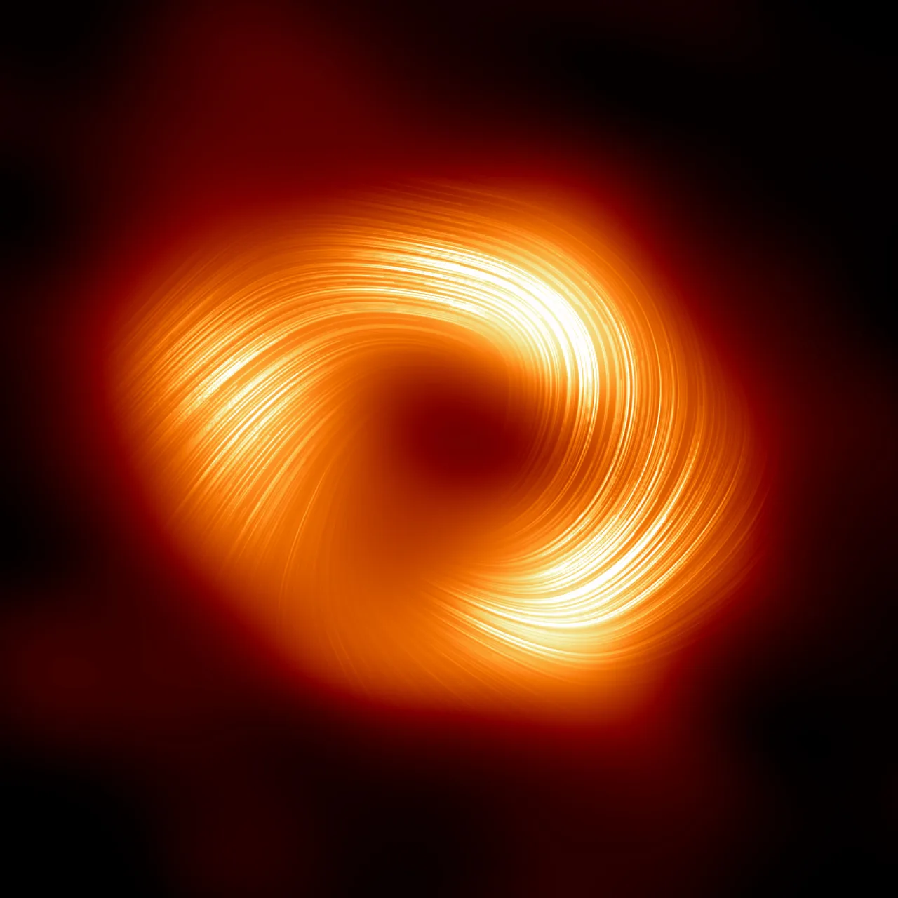 Samanyolu galaksisinin merkezindeki süper kütleli kara delik Sagittarius A*'ın polarize ışıkta görüntüsü: ortada koyu bölge, etrafında ince çizgi desenli parlak halka