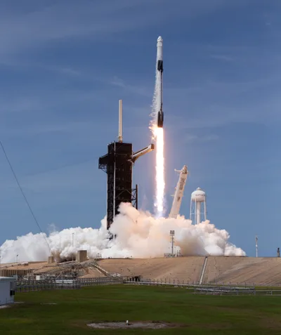 A Falcon 9 rocket lifting off from the Kennedy Space Center, with a column of flame and rising smoke