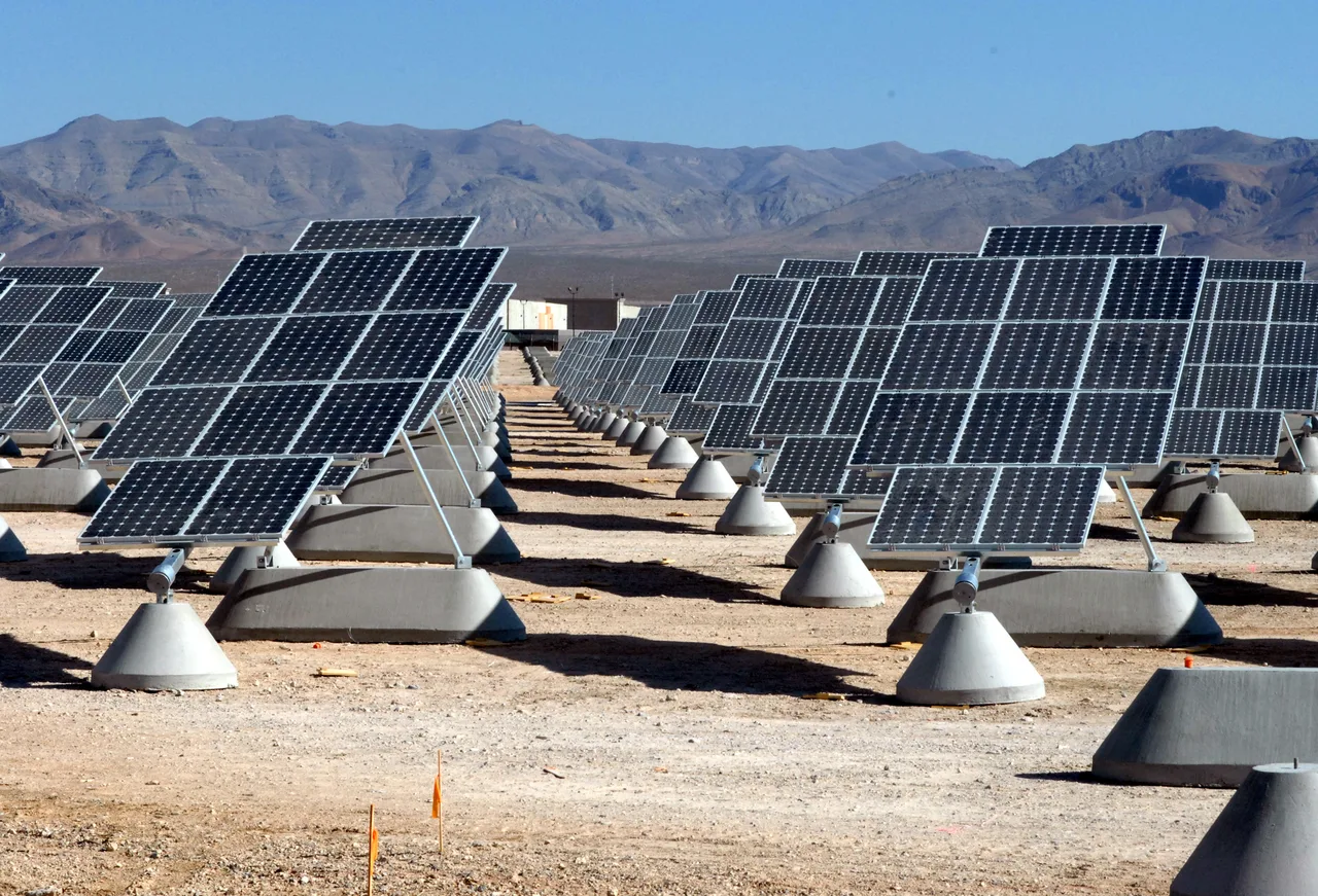 Nellis Air Force Base, Nevada — thousands of photovoltaic solar panels arranged in long rows across a desert landscape; a mountain range in the background