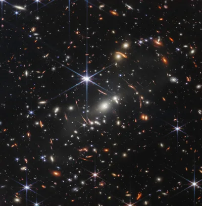 Webb's First Deep Field: thousands of galaxies in the black void; some bent and stretched into arcs by the gravity of a foreground cluster