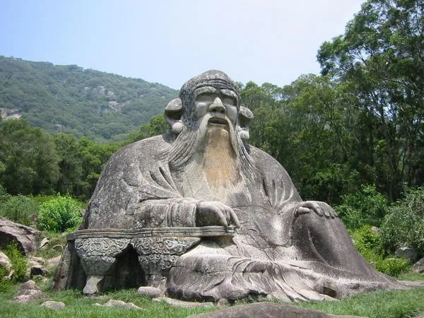 Monumental stone statue of Lao Tzu on Mount Qingyuan in Fujian, China, depicting him as a bearded, smiling old sage