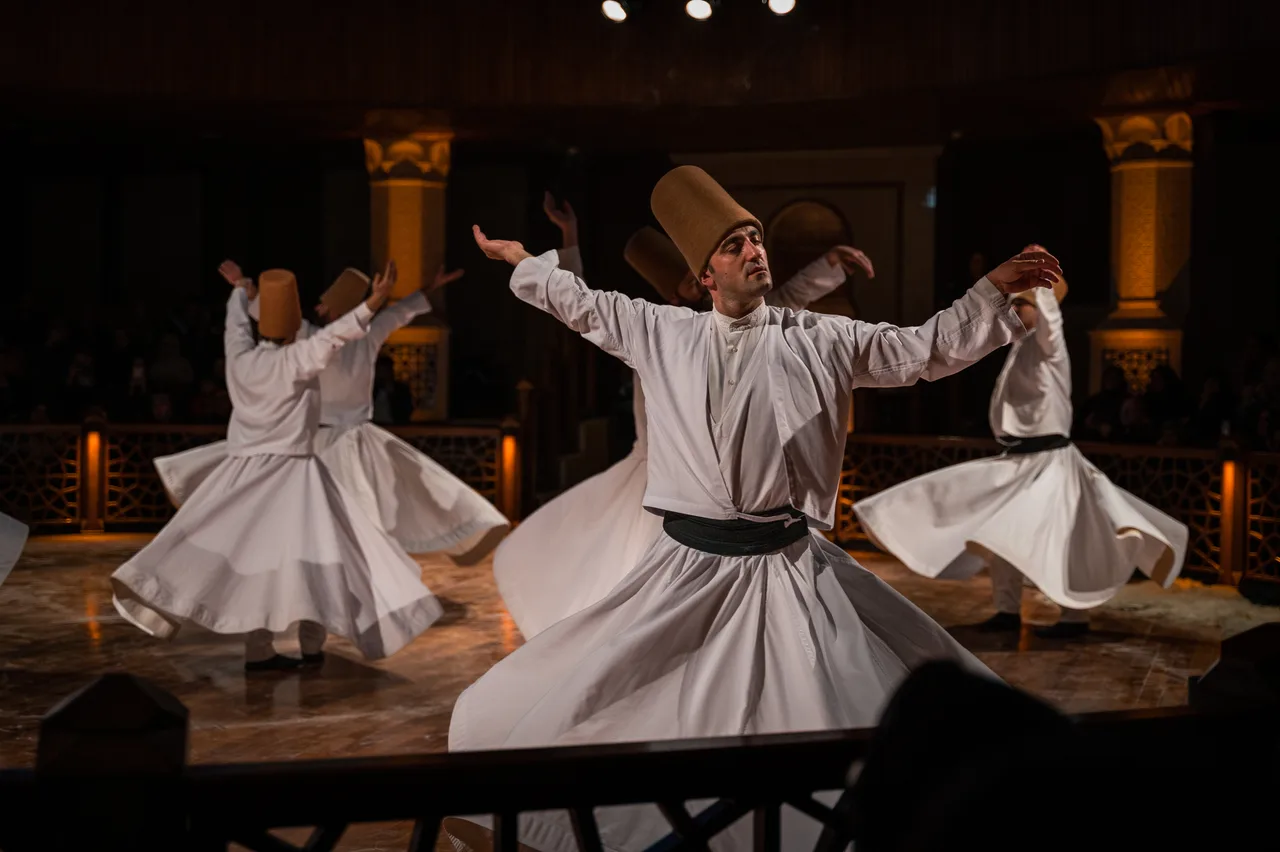 Konya'da uzun beyaz tennureler ve kahverengi sikke (külah) giyen Mevlevi dervişler sema törenini icra ederken — kollar açık, sağ el yukarı sol el aşağı dönük
