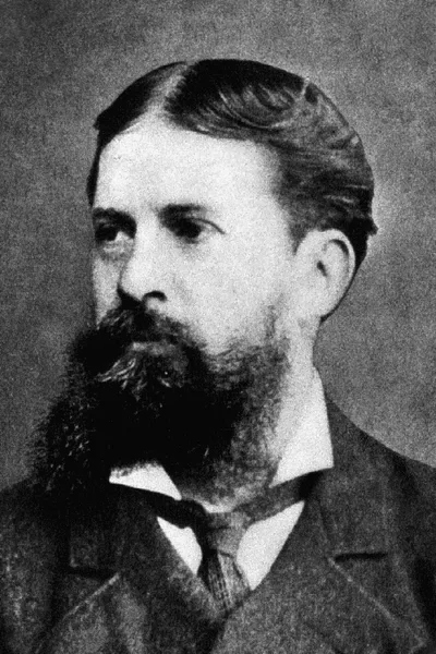 A black-and-white portrait of Charles Sanders Peirce: a bearded nineteenth-century scholar in a dark coat