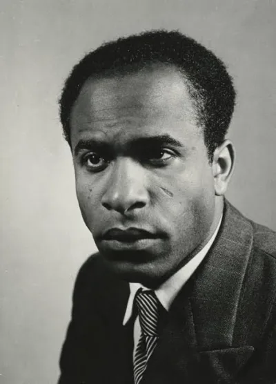 Black-and-white portrait photograph of Frantz Fanon: a young man in a suit with a serious gaze